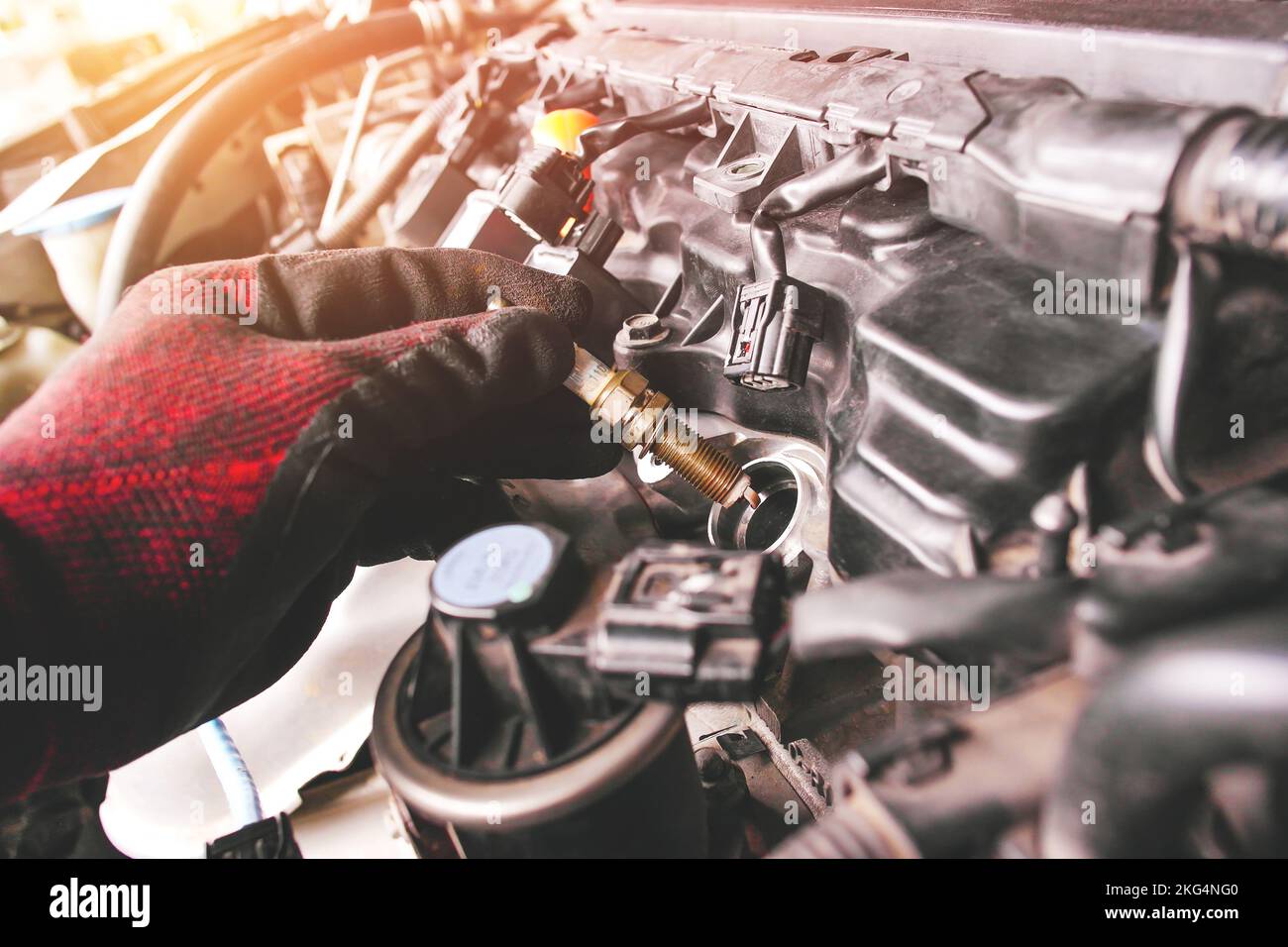 A auto mechanic is installing automobile iridium spark plugs into the