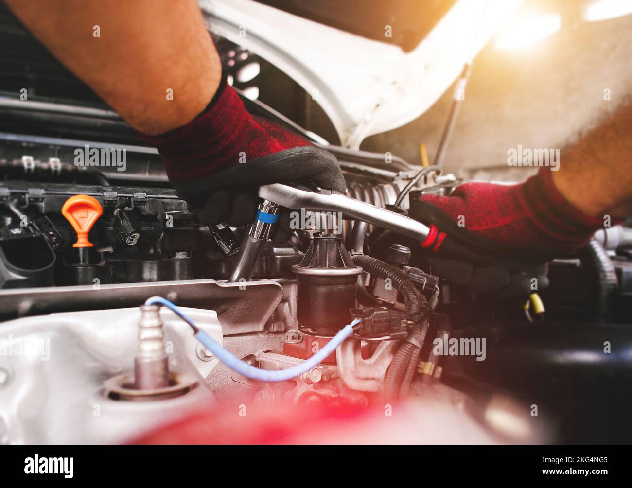 Engine Inlet Fastening The red gloved hand of the auto mechanic is fastening the bolt with the ...