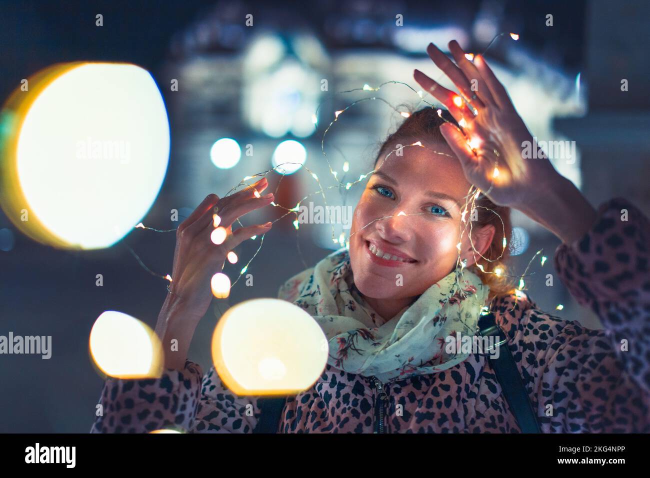 Young white woman holding LED garland at night portrait with bokeh, horizontal Stock Photo