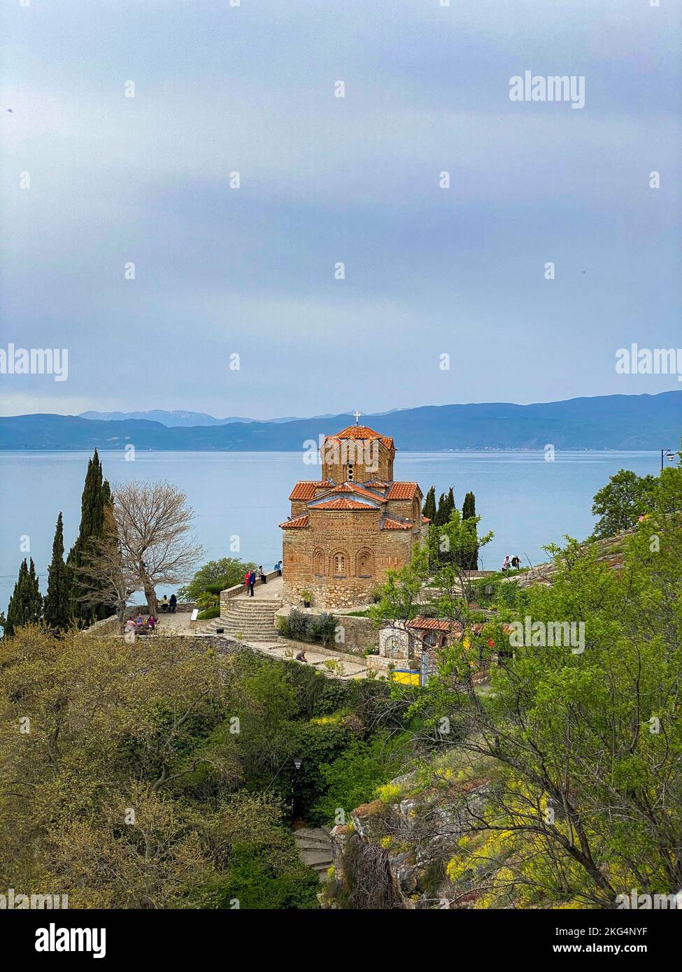 A vertical shot of the Church of Saint John the Theologian on the cliff with Lake Ohrid in the back Stock Photo