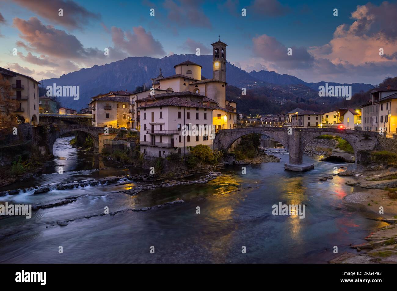 Aerial villagescape - old church and crossing rivers with mountains backdrop, San Giovanni Bianco Village, Valbrembana, Bergamo, Lombardy, Italy Stock Photo