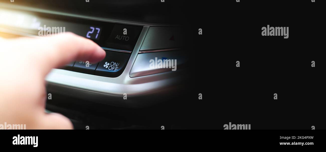 The driver hand is pressing the on-off button of the car air ...