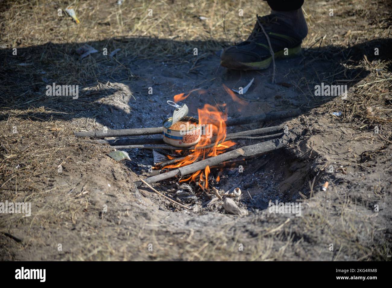 Heating a tuna can on a improvised camp fire. Challenging living conditions in a transit migrant