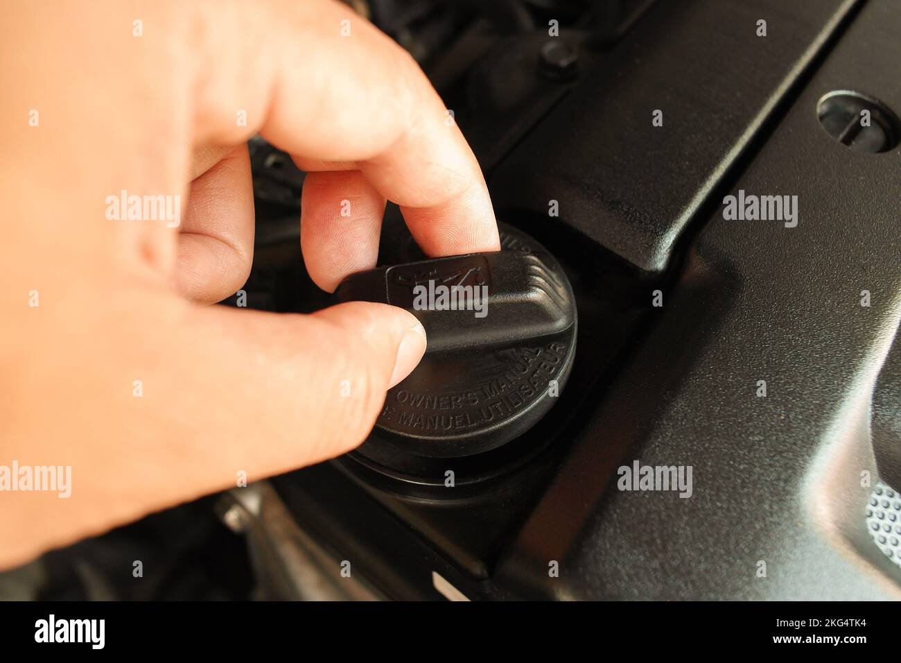 The auto mechanic is opening the oil cap to fill the motor oil to engine , auto maintenance service concept Stock Photo