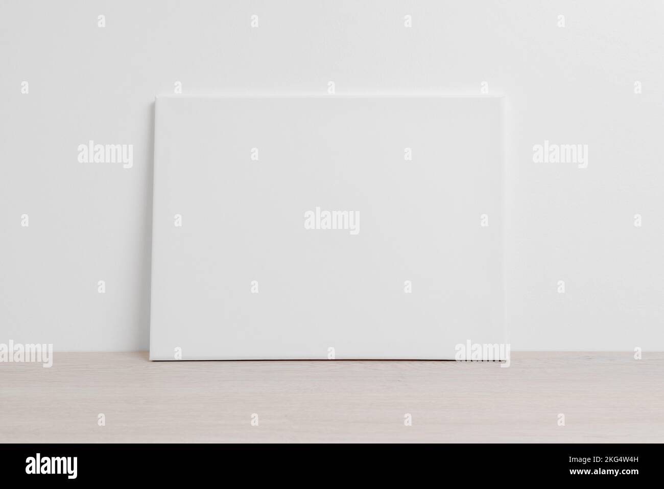 Art canvas in a horizontal position on the floor leaning against a white wall. Clean cloth for mockup art presentation Stock Photo