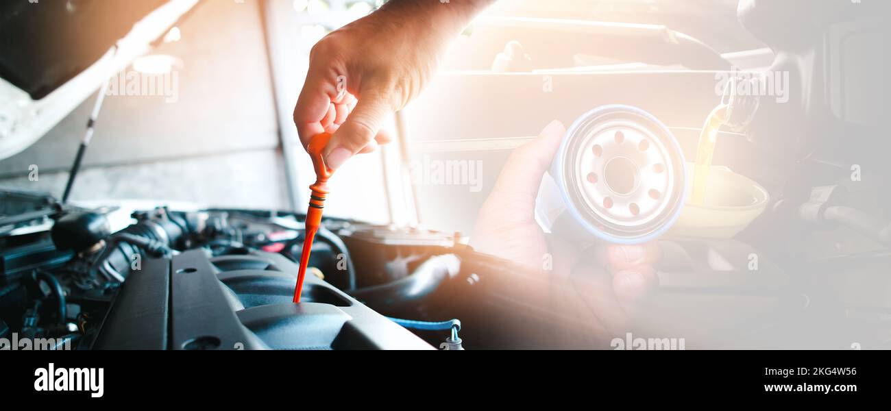 The mechanic is pulling the lube dipstick and oil filter in the hand with oil pouring to engine, double exposure on background, auto maintenance servi Stock Photo