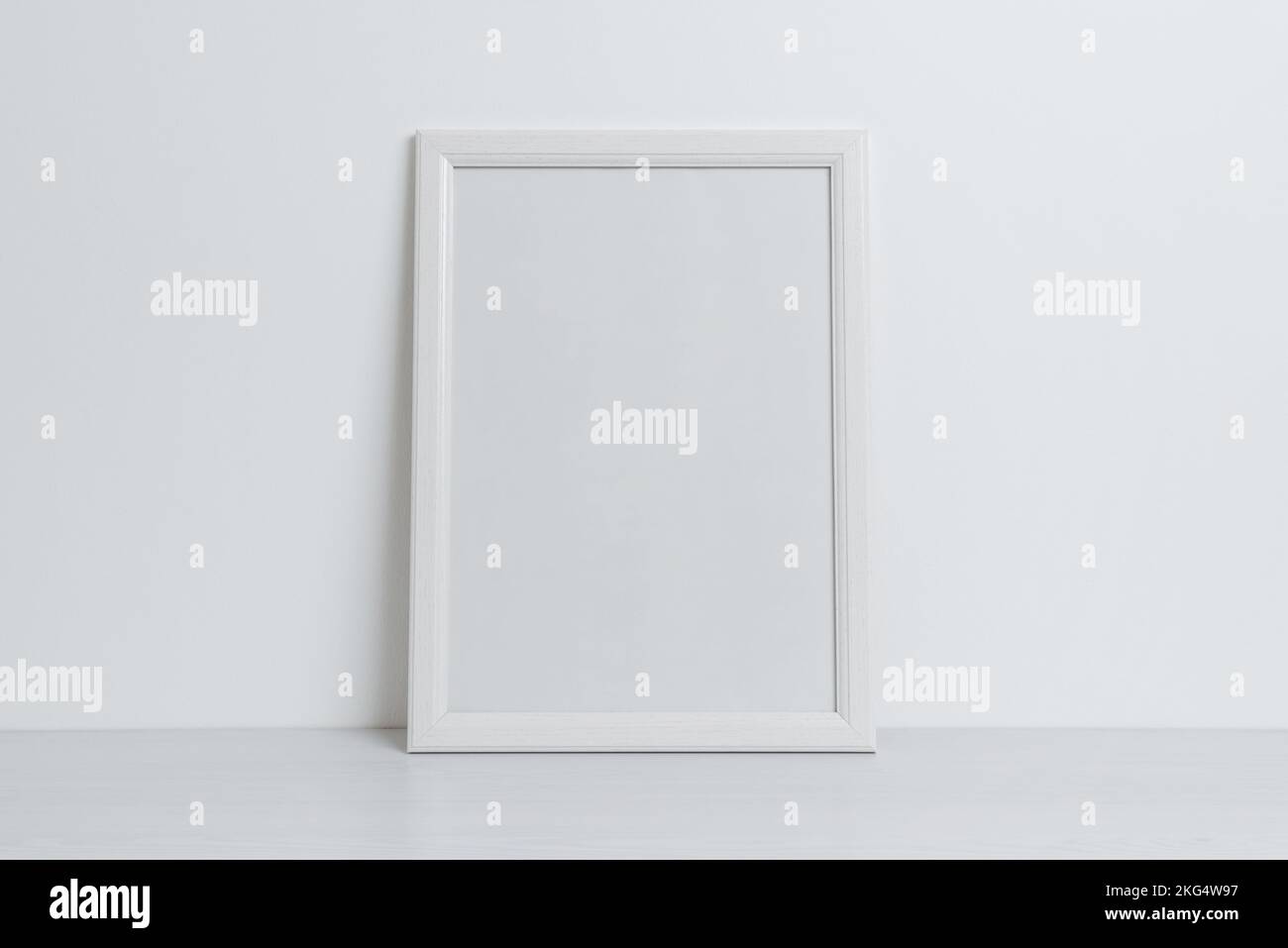 White picture frame mockup leaning against the wall. Clean, blank surface for art presentation Stock Photo