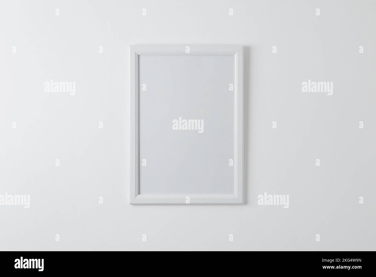 Empty picture frame mockup on clean wall. Blank surface for copy or art presentation. White wooden frame Stock Photo