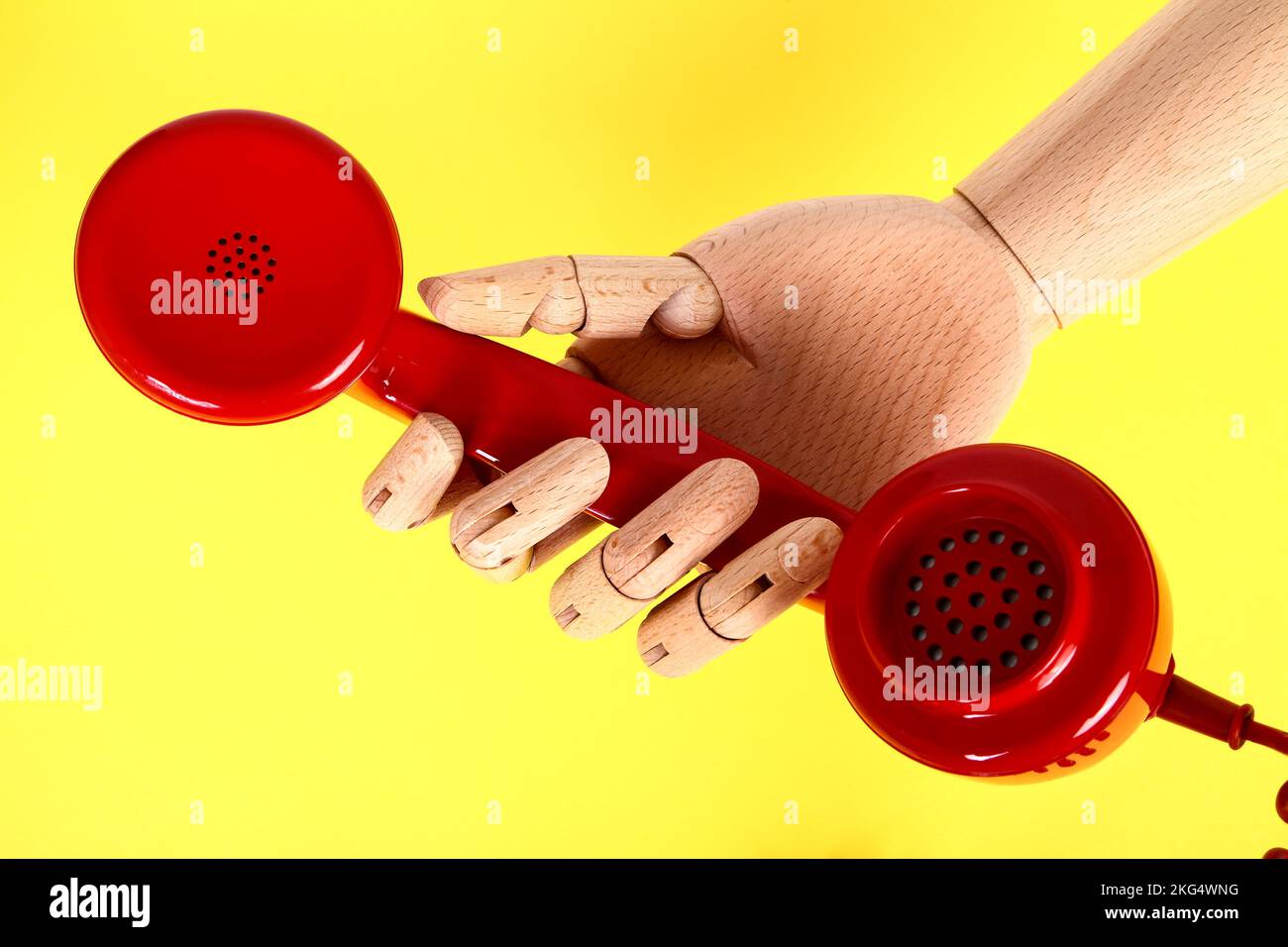 Wooden hand holding a red old fashioned retro telephone handset Stock Photo