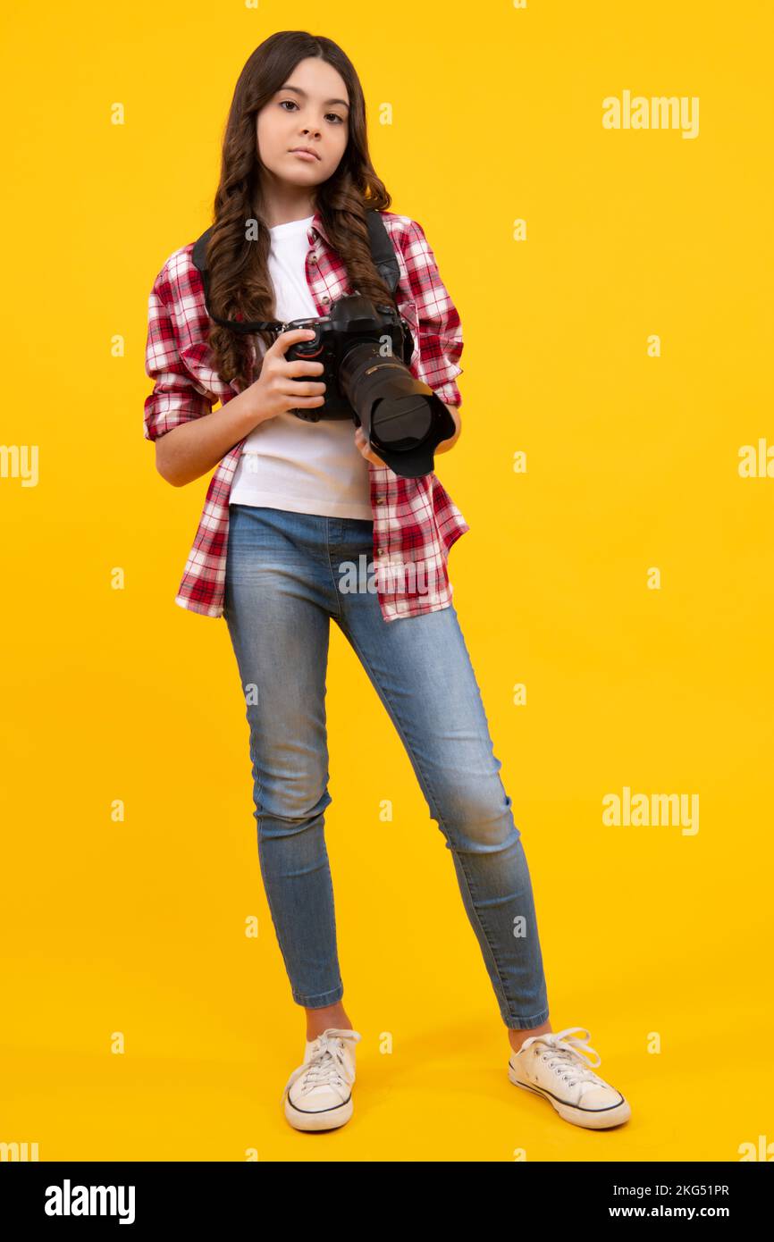 Teenager girl with dslr photo camera with zoom lens. Child photographer isoalted on yellow background. Photo school. Shooting with professional camera Stock Photo