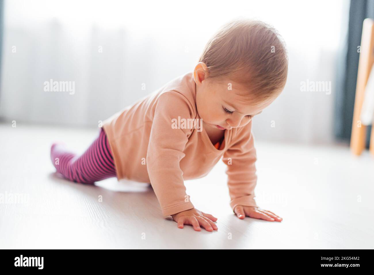 A girl child learns to crawl the floor. First steps Stock Photo
