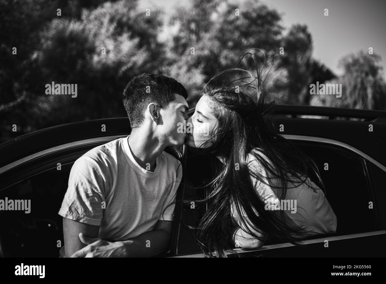 A couple kisses in the car while traveling black and white photo Stock