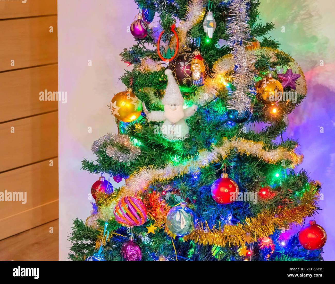Decorated Christmas tree on white wall background in the corner of the ...