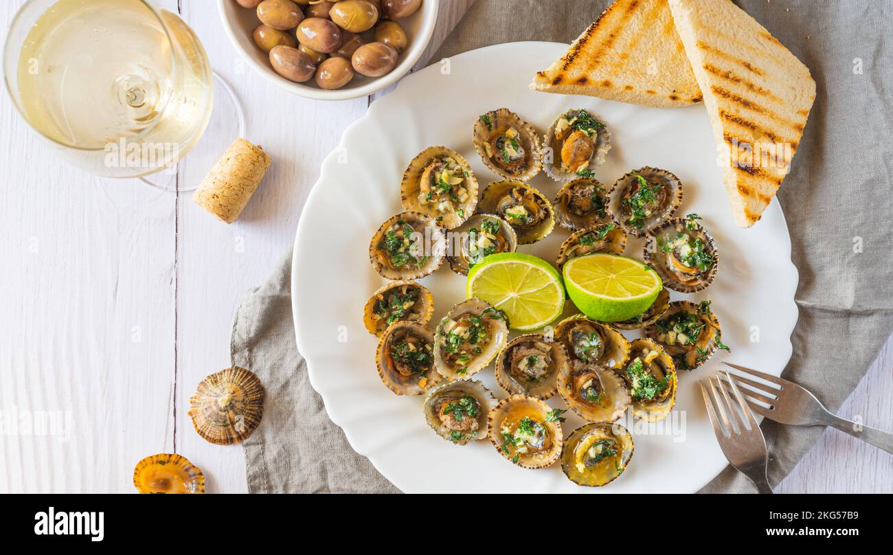 Limpets molluscs with lime and a glass of whine Stock Photo