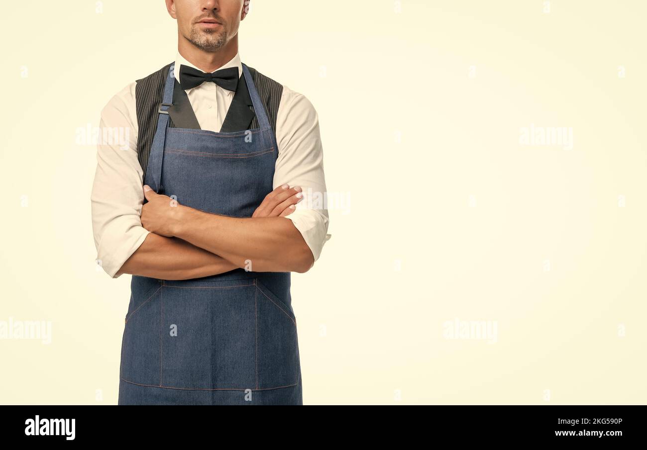 Confident man crop view in bow and bartender apron keeping arms crossed isolated on white, copy space Stock Photo