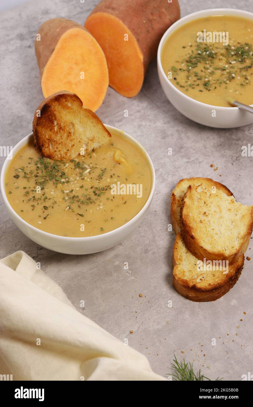 sweet potato puree soup with garlic bread on grey marble table Stock