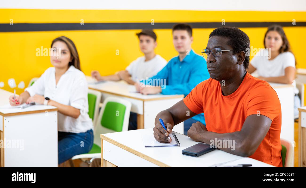 Multiethnic group of people studying together at tables. Focus on African american man Stock Photo