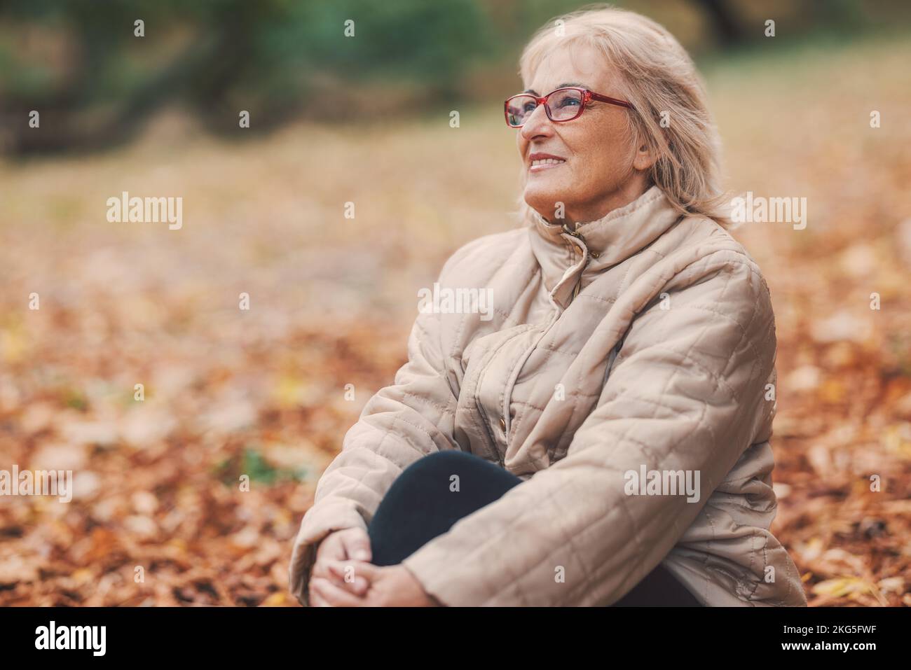 Happy beautiful senior woman enjoying nature in park in autumn Stock Photo