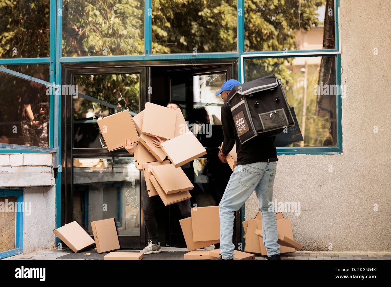 Reckless courier dropping pizza boxes pile at client, clumsy courier carrying office food order outdoors. Bad delivery service, careless clumsy man with falling fastfood packages stack Stock Photo