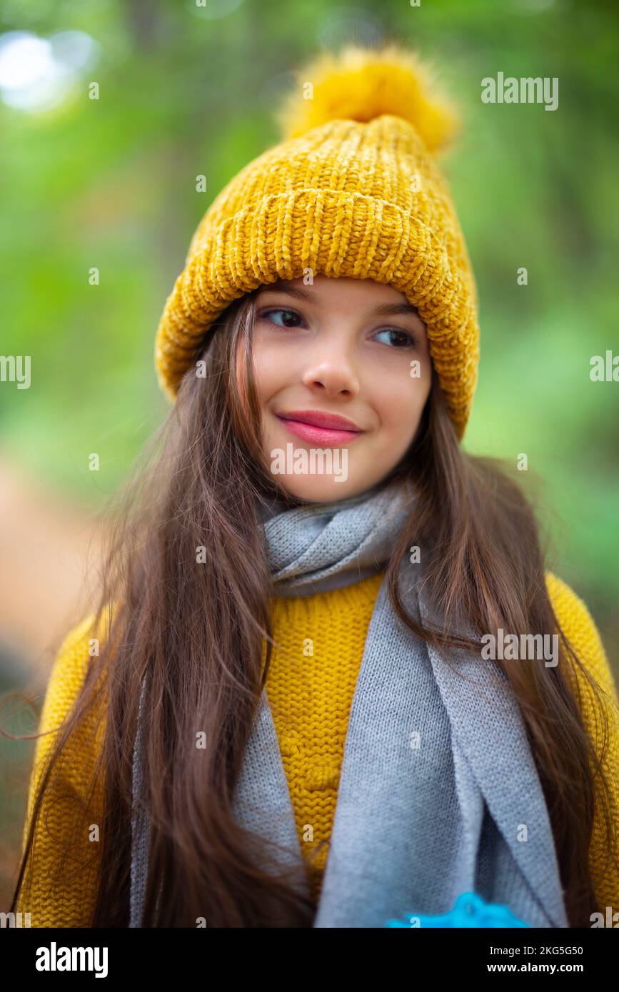 Portrait of beautiful girl or young woman outdoor in autumn forest. Lady with winter hat and scarf. Stock Photo