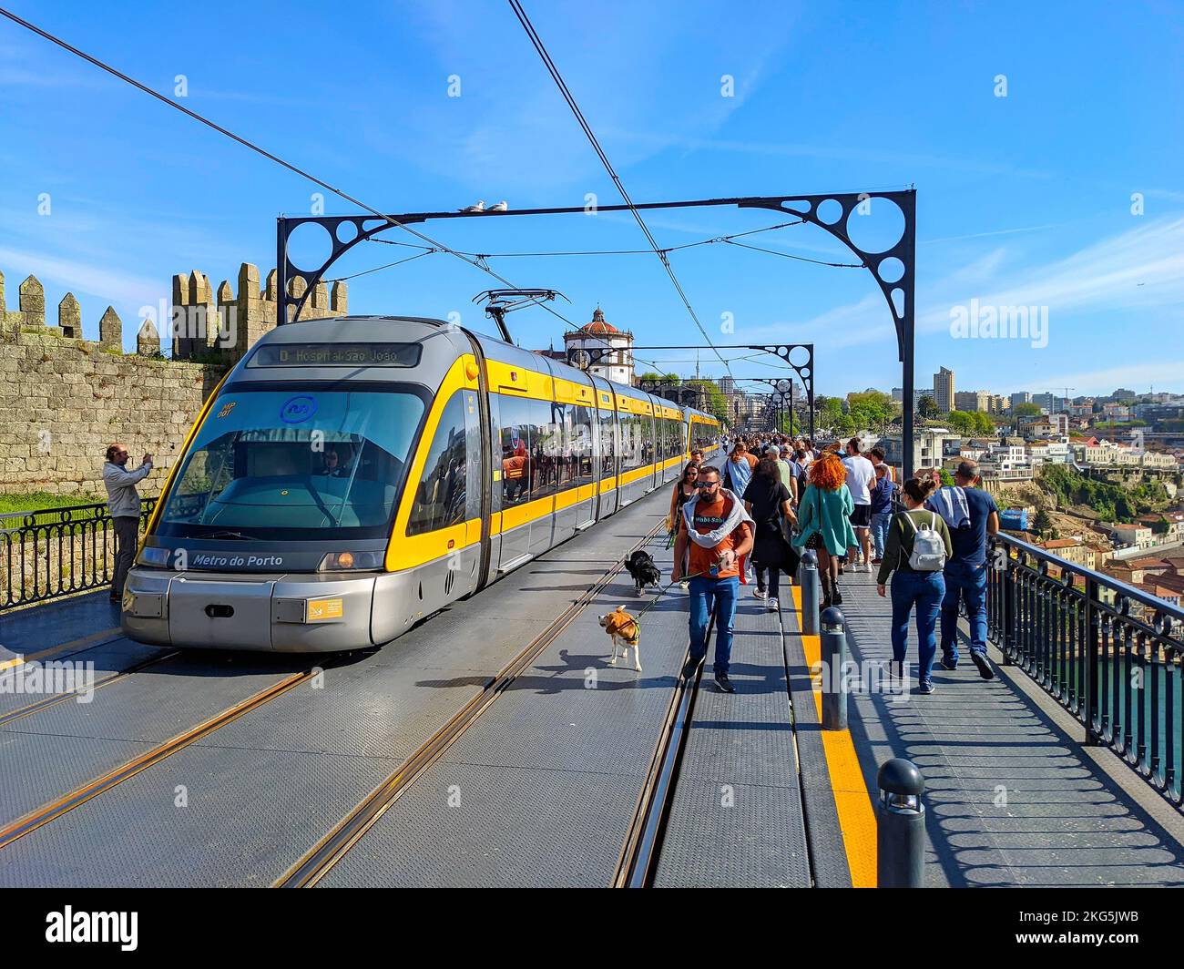 PORTO, PORTUGAL - APRIL 15, 2022: People walking at Dom Luis bridge with dogs, crowd of tourists, metro train, sunshine day Stock Photo
