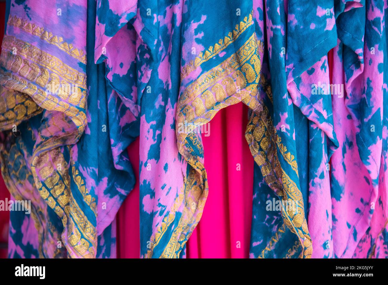 Background of colorful draped overlapping fabrics in pinks and turquoise with gold yellow embroidered design -boho or gypsy look Stock Photo