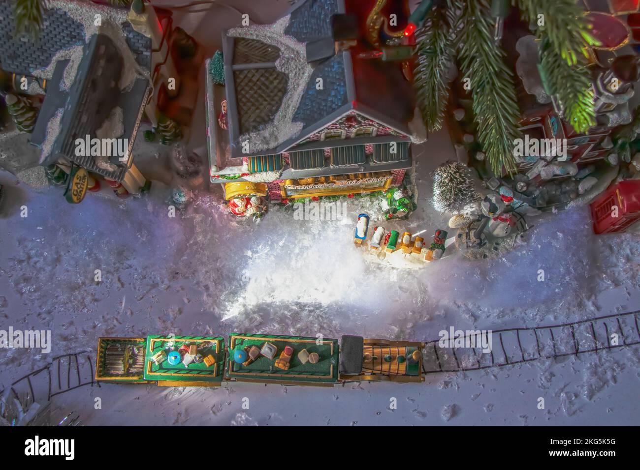 Looking down at under-the-tree Christmas village with train with presents on top and Santas Workshop and a gas station and mailboxes and snow - at nig Stock Photo