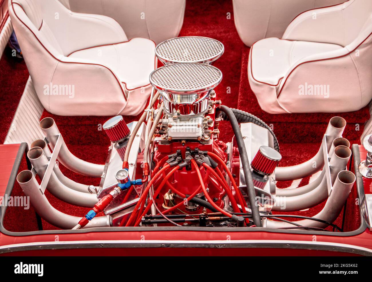 Open loud retro vintage red fiberglass speed boat motor with spark plugs and pipes in back behind seats - boat show Stock Photo