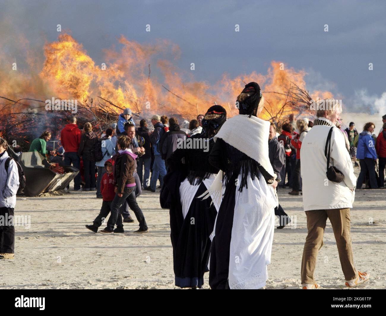 Midsummer fire, Tourists and two women in frisian costumes, beach of Amrum, North Frisian Islands, Germany Stock Photo