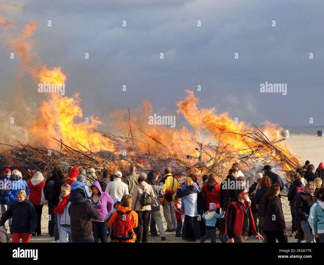 Midsummer fire, Tourists and two women in frisian costumes, beach of Amrum, North Frisian Islands, Germany Stock Photo