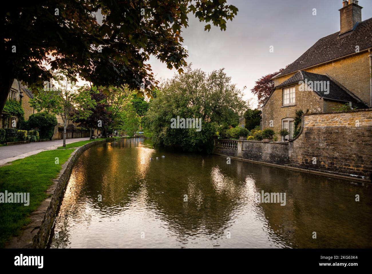 Stone cottage and balustrade on the River Windrush in Bourton-on-the-Water in the Cotswolds, England, a UK Conservation Area. Stock Photo