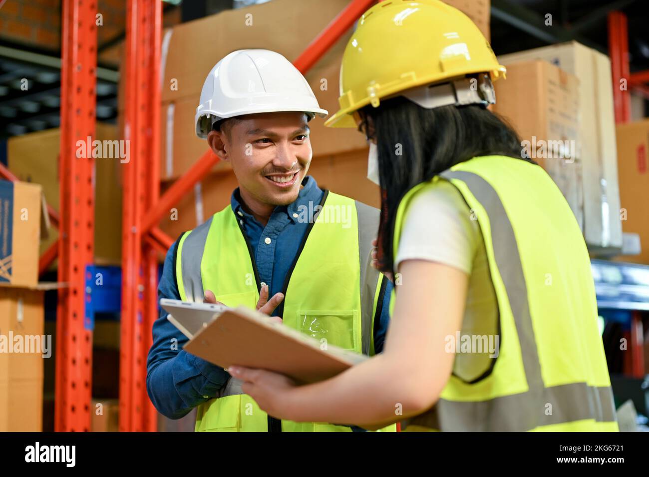 Smart and professional millennial Asian male warehouse manager talking and working with a young female colleague. industrial workplace concept Stock Photo