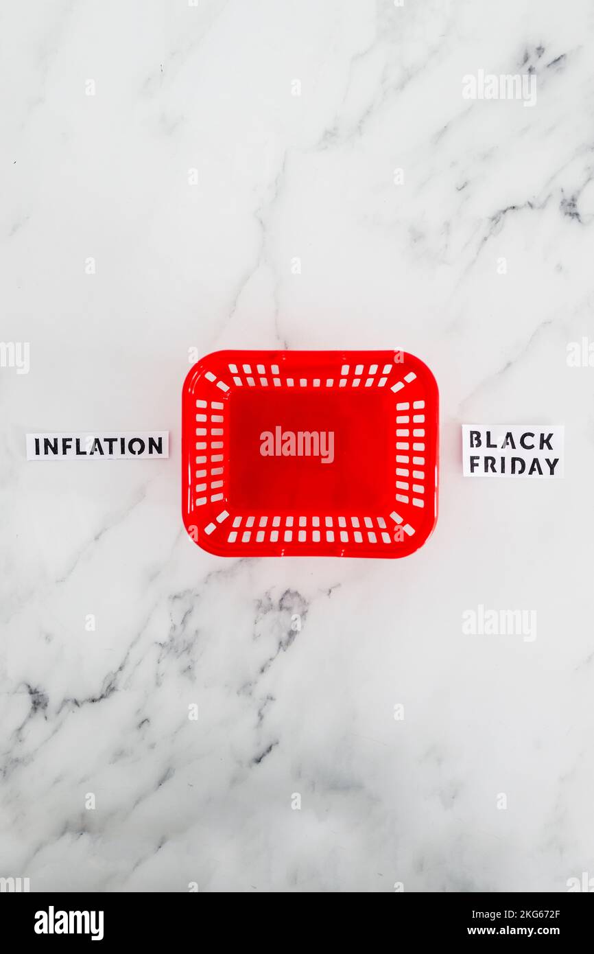 Inflation vs Black friday conceptual image with red empty shopping basket in between opposite concepts about consumer spending Stock Photo