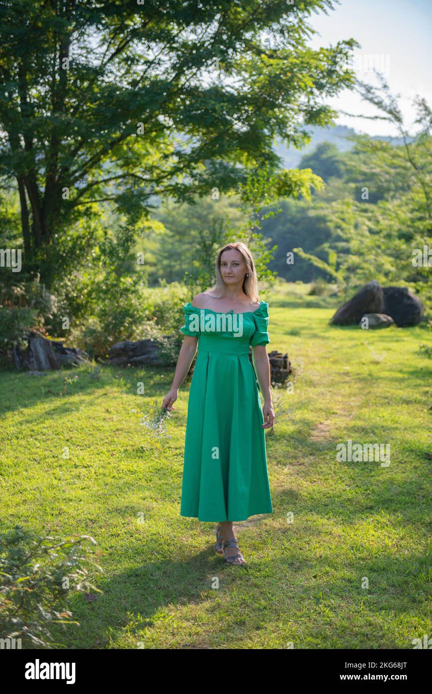 a girl in a green dress is standing in a clearing Stock Photo - Alamy