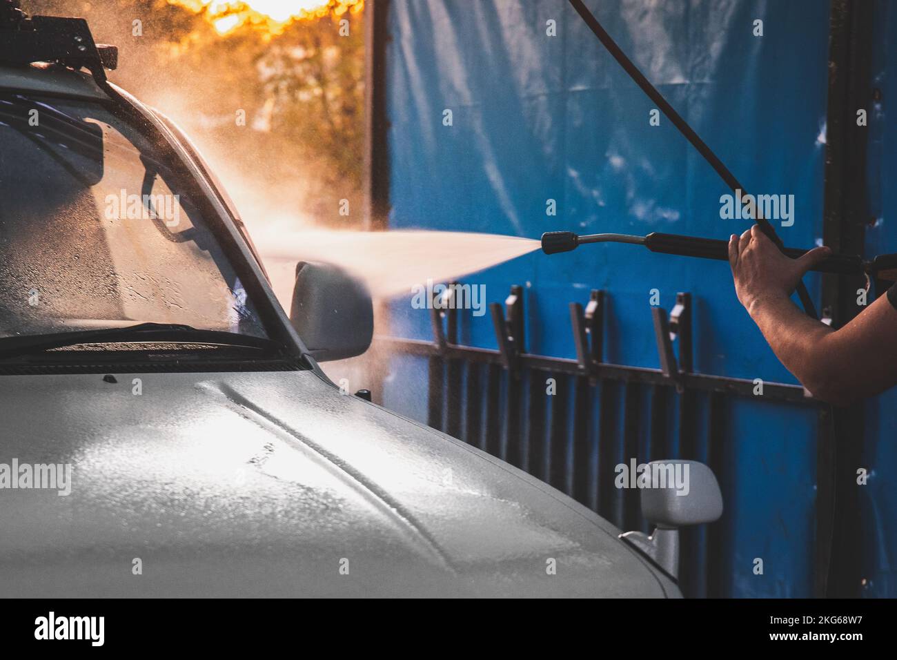 Human hand washing white car on contactless selfservice car wash with