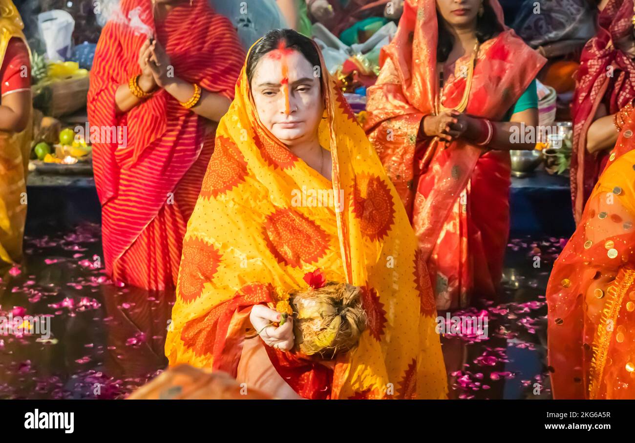 women devotee standing in river and praying with religious offerings for sun god in Chhath festival Stock Photo