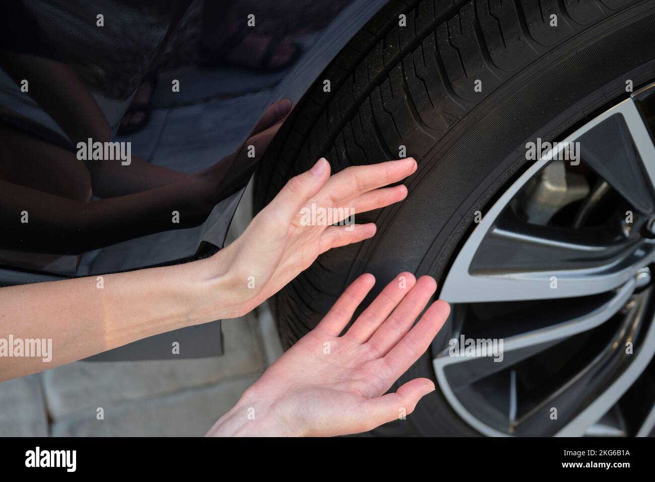 Female driver hands inspecting wheel tire of her new car. Vehicle safety concept Stock Photo