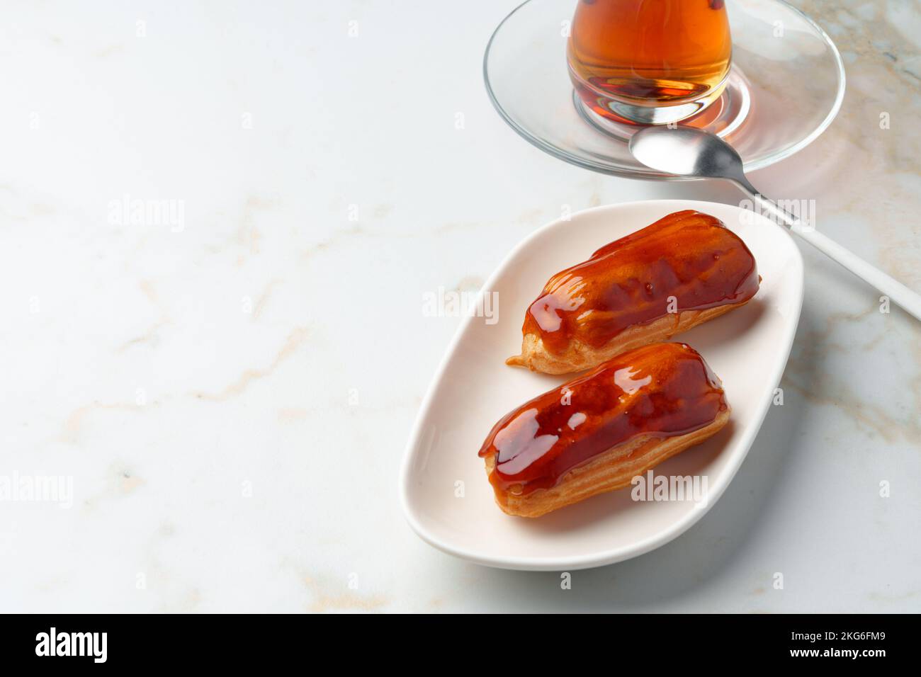 Two caramel eclairs on a white plate Stock Photo