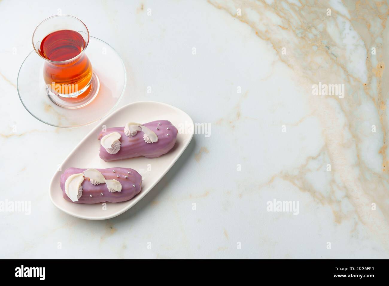 Two eclair cakes with violet frosting on white plate Stock Photo