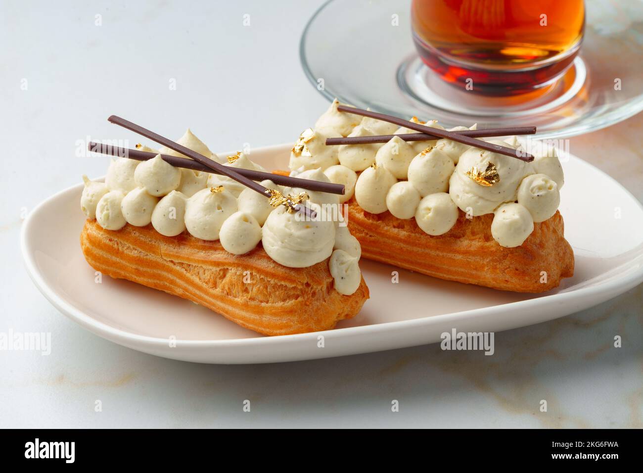 Two eclairs with white custard on whhite plate Stock Photo