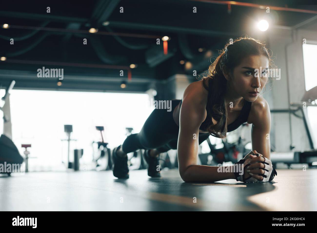Young woman doing plank exercise while exercising in gym. Stock Photo