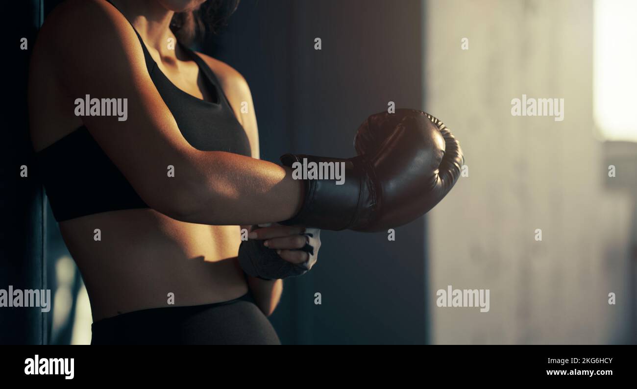 Close-up young woman wearing boxing glove in the gym. Stock Photo