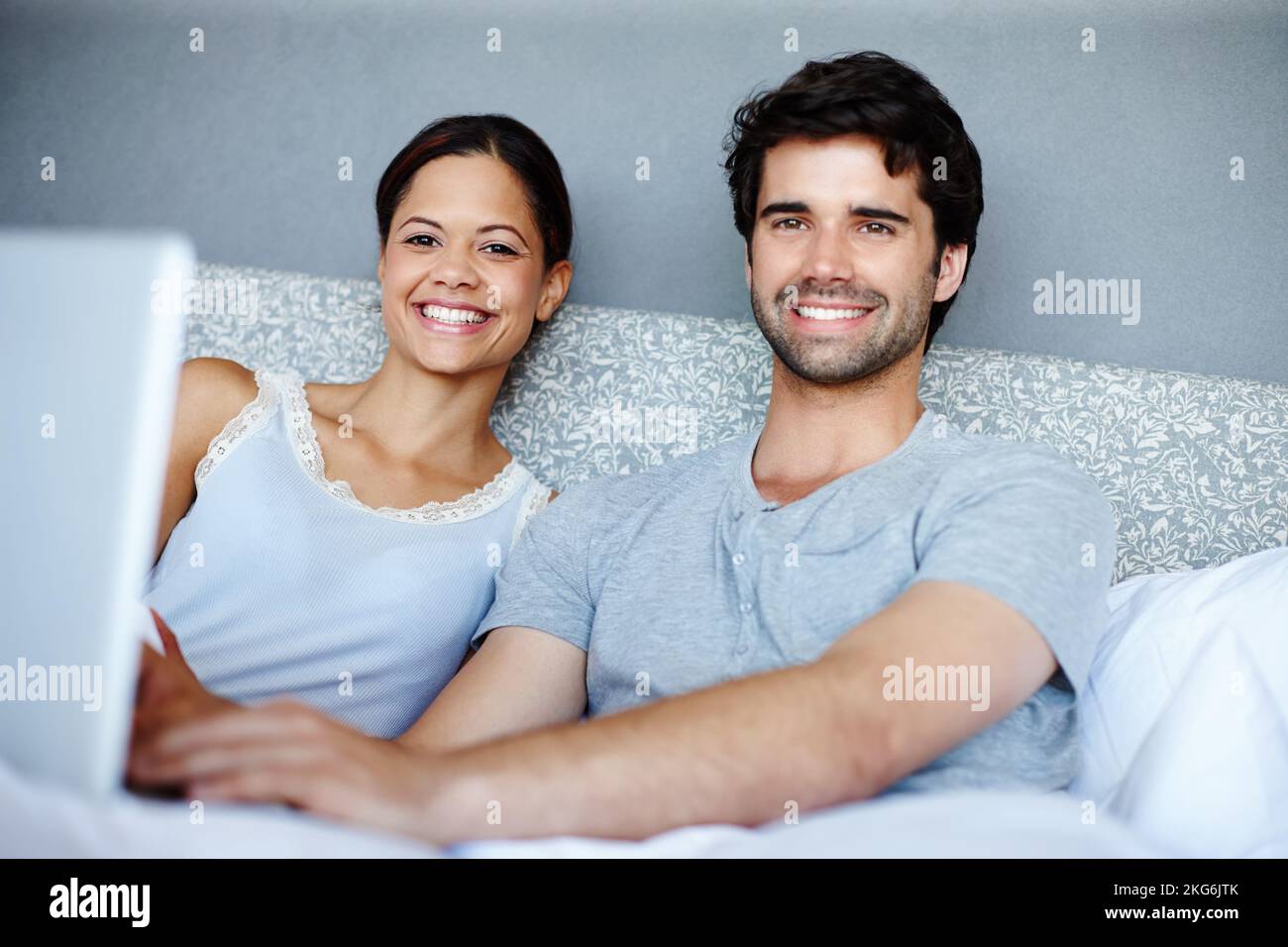 Comfy in bed with technology. Attractive couple in bed looking at a