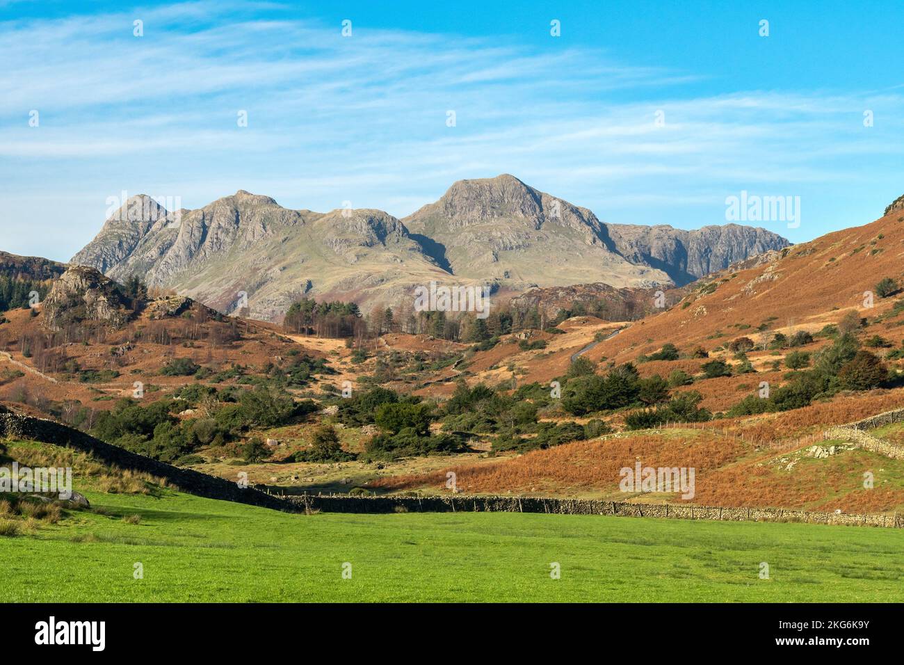 Langdale Pikes mountain range as seen from lush green farm fields in Little Langdale valley, English Lake District, Cumbria, England, UK Stock Photo