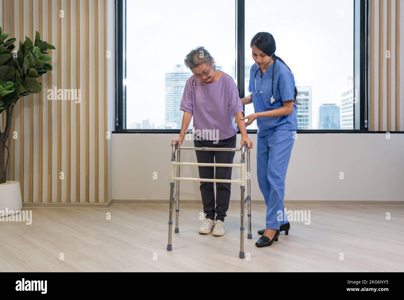 Woman physical therapist in blue uniform help an elderly to exercise