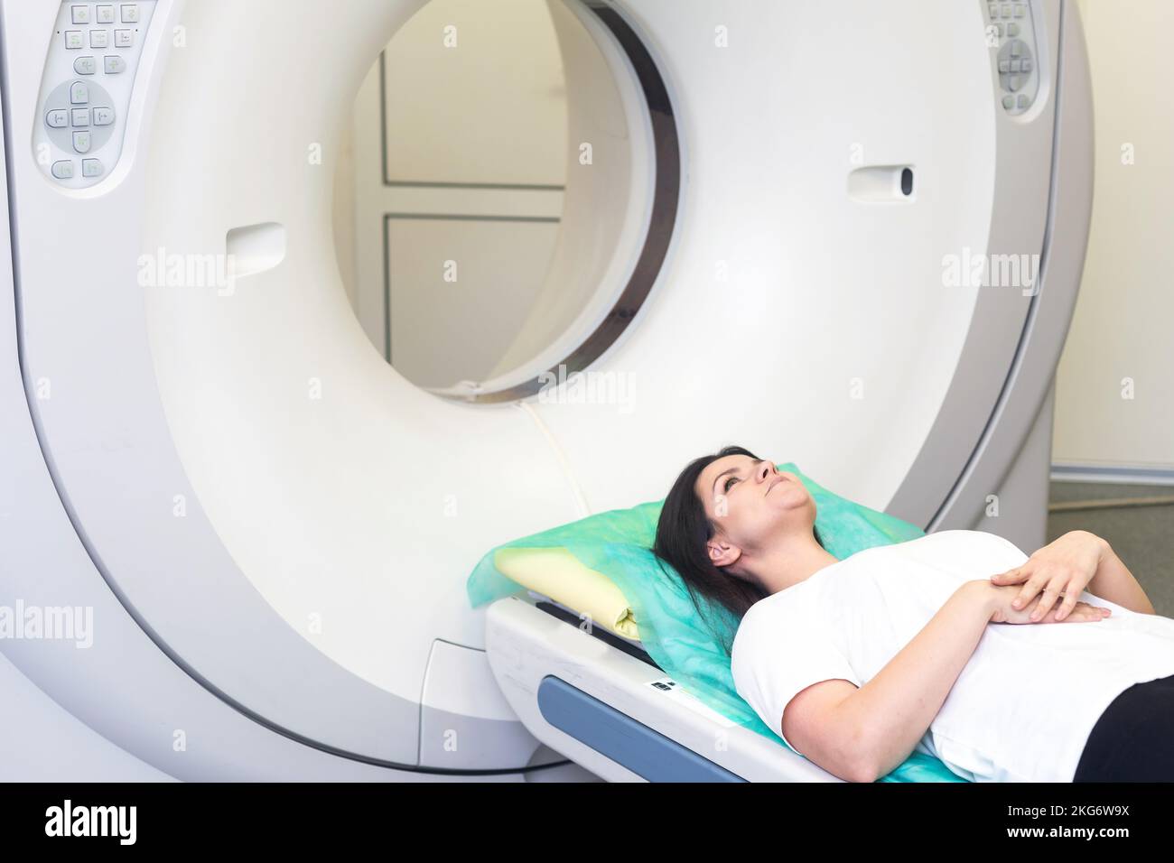 CT scan technologist overlooking patient in Computed Tomography scanner