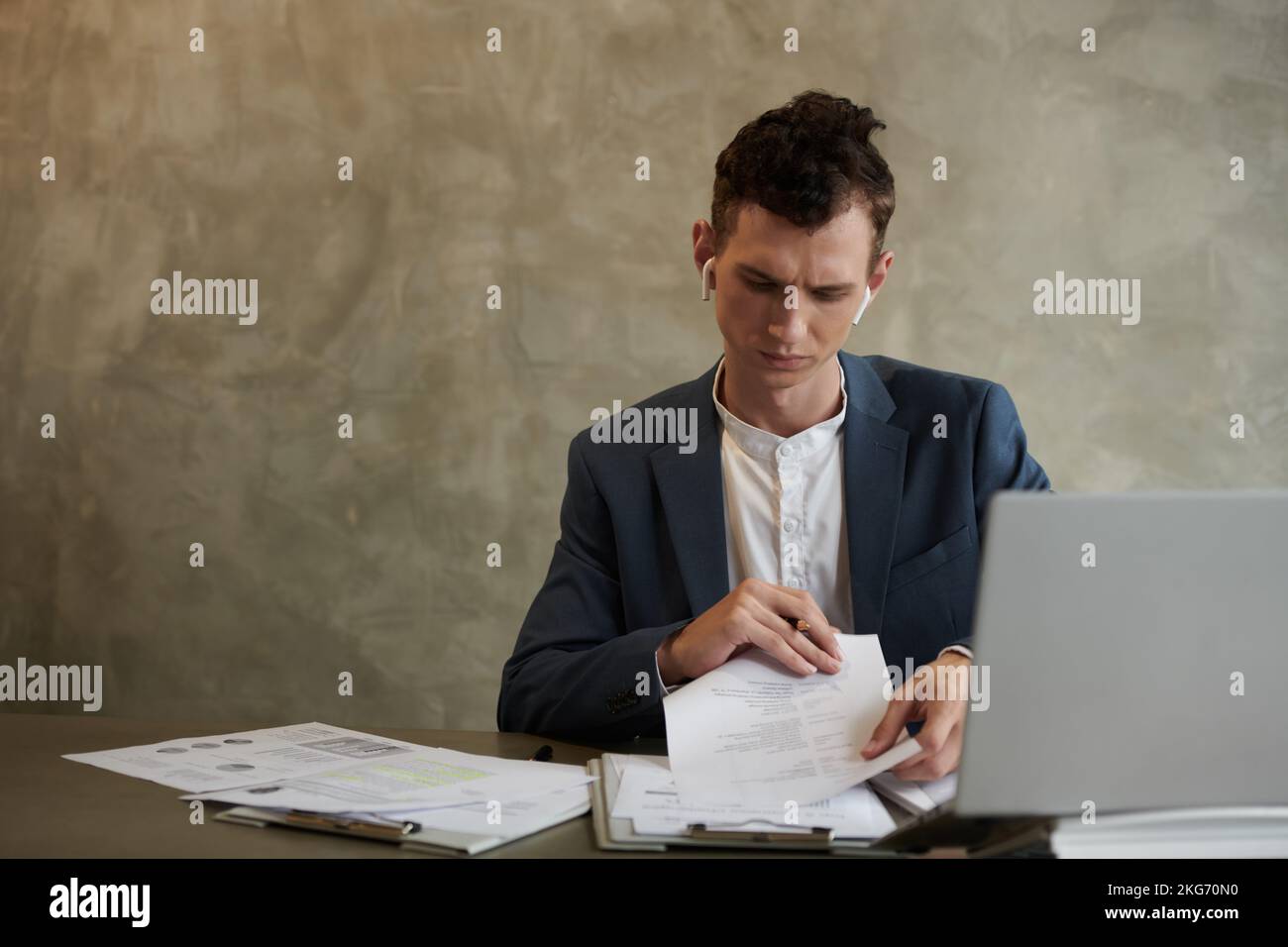 Frowning young entrepreneur working with documents at office desk Stock Photo