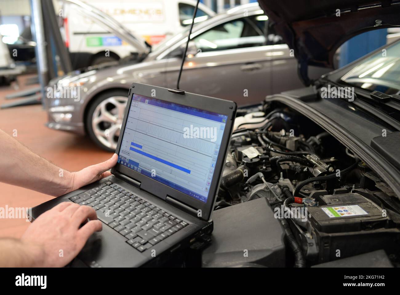 mechanic in a workshop checks and checks the electronics of the car - software update with a modern computer Stock Photo