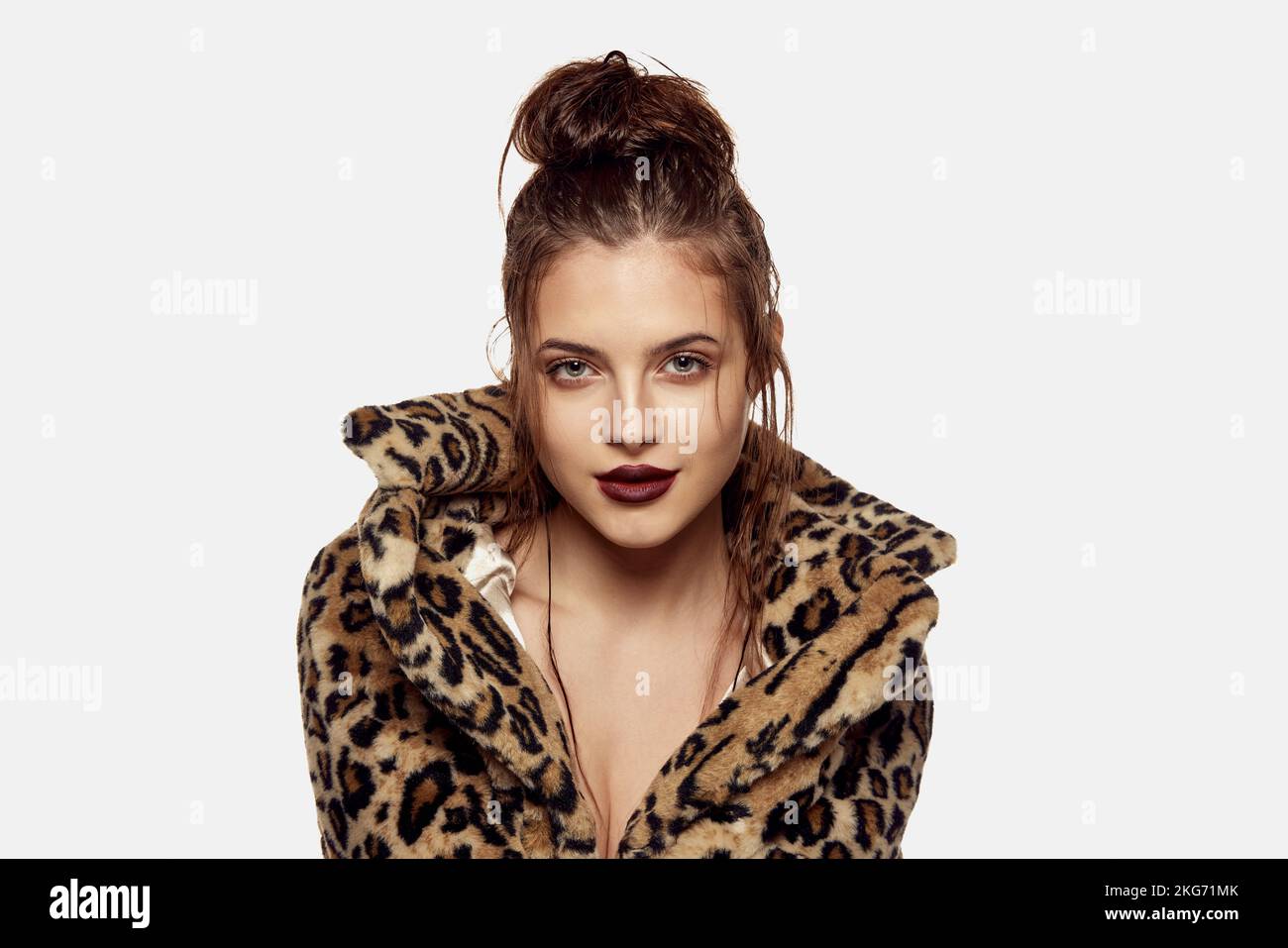 Portrait of young beautiful girl posing in stylish animal print coat isolated over white background. Messy wet hair look. Concept of beauty, fashion Stock Photo