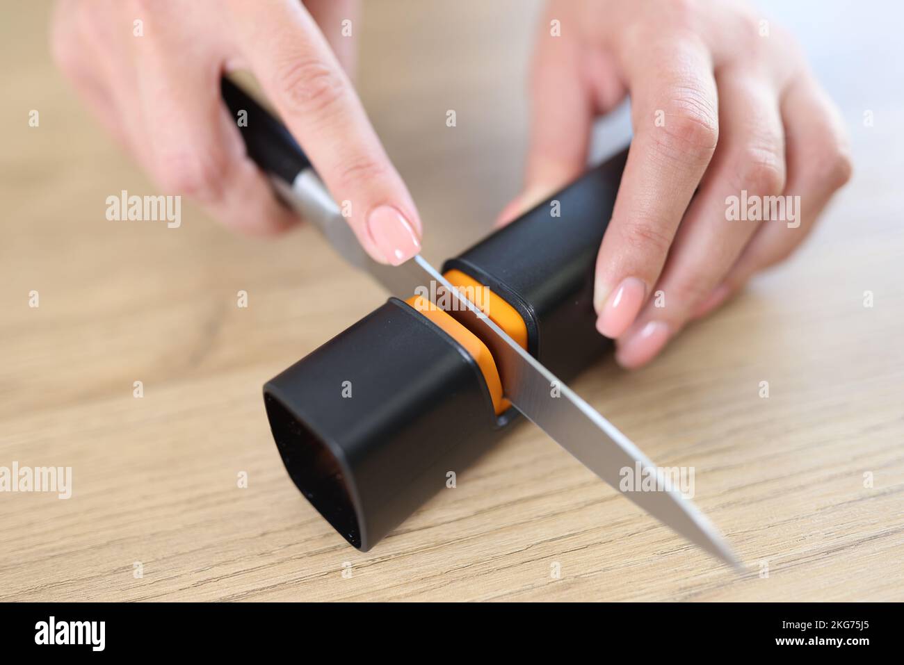 Female hands sharpening knife with special knife sharpener Stock Photo